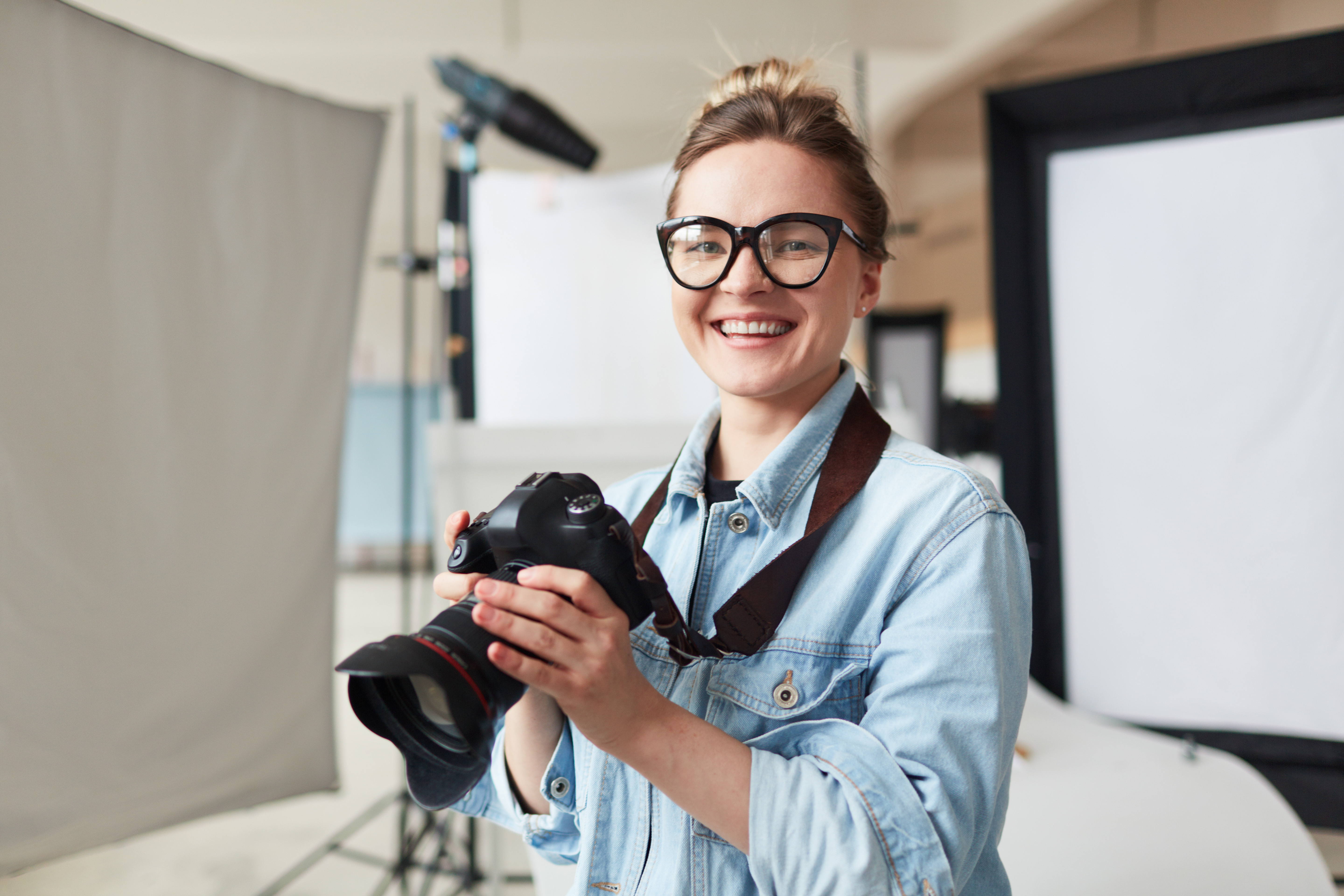 Lächelnde Fotografin hält eine Profikamera in ihren Händen